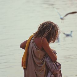 Rear view of beggar standing at lakeshore