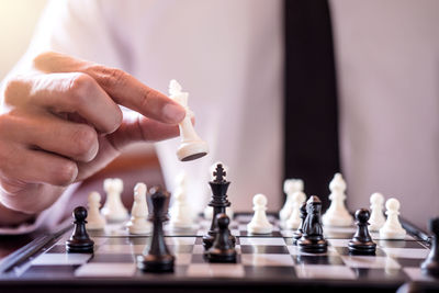 Midsection of businessman playing chess board