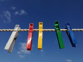 Low angle view of clothespins hanging on clothesline against sky