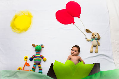 Side view of a boy with balloons against wall