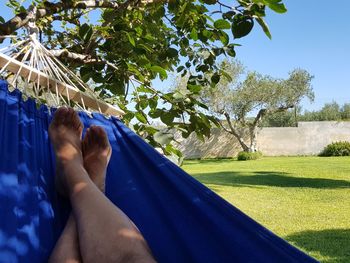 Low section of man relaxing on hammock at swimming pool