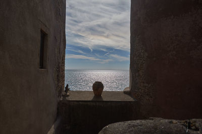 Woman by sea against sky