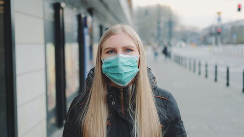 Portrait of young woman wearing mask standing outdoors