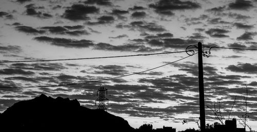 Low angle view of power lines against cloudy sky