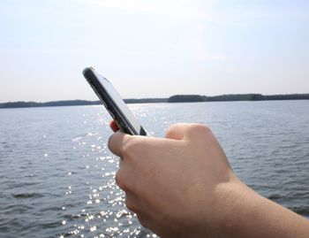 Midsection of person holding sea against sky