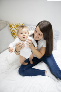 High angle view of mother and daughter sitting on bed at home