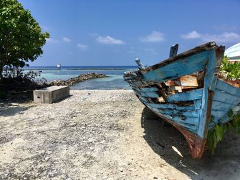 Abandoned boat on beach against sky