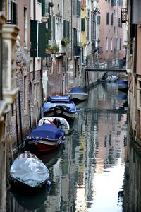 Boats moored in canal amidst buildings in city