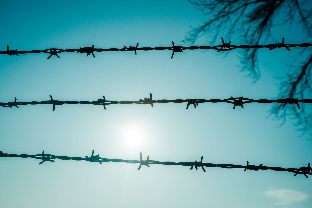 LOW ANGLE VIEW OF BARBED WIRE FENCE AGAINST SKY