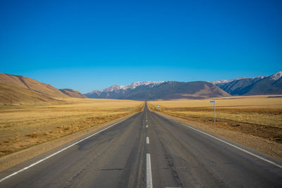 Empty road against clear blue sky