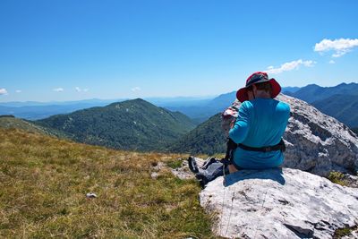 Senior woman sitting on mountain peak with beautiful view in background - velebit mountain, croatia