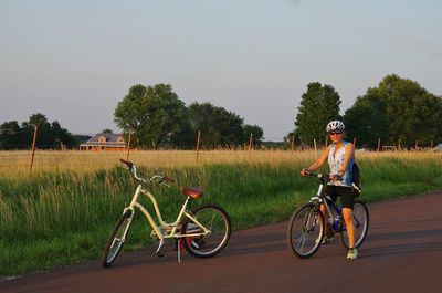 Man riding bicycle on field against clear sky