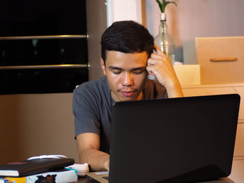 Mid adult man using mobile phone while sitting on table