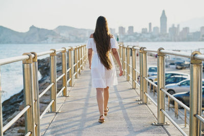 Rear view of woman standing against railing in city