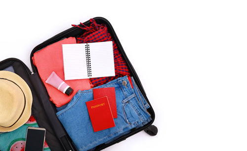 High angle view of luggage with hat and clothes on white background