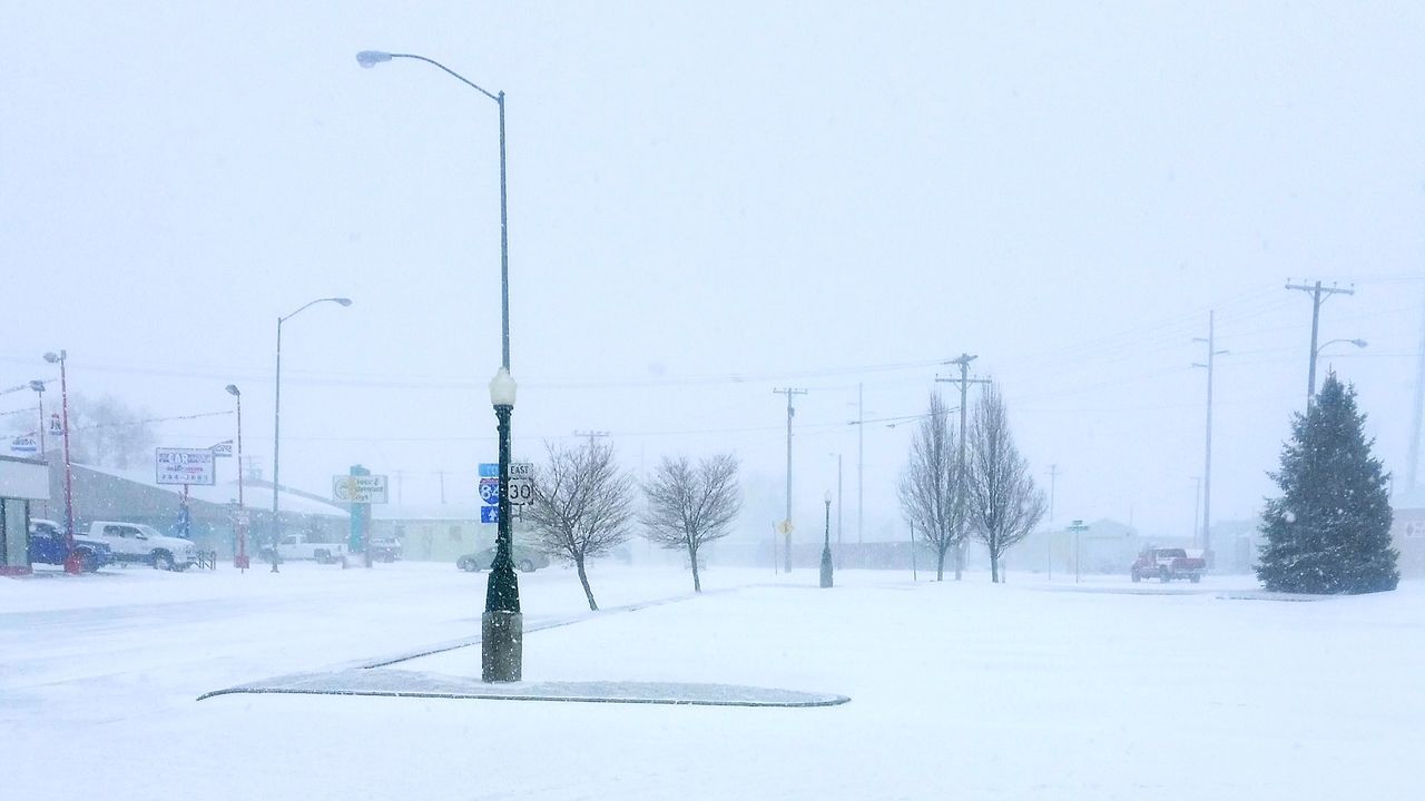 SNOW COVERED STREET AMIDST FIELD AGAINST SKY