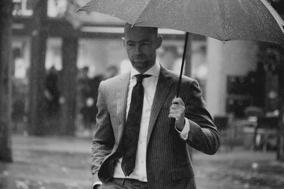 Man with umbrella walking on road in rain