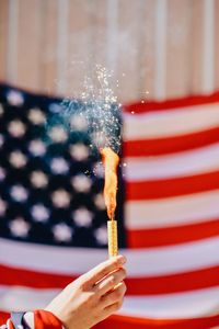 Cropped hand holding distress flare against american flag