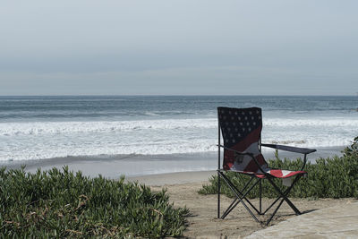 Deck chairs on beach against sky