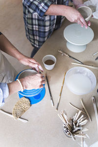 High angle view of female potters molding shape from clay at workbench in store