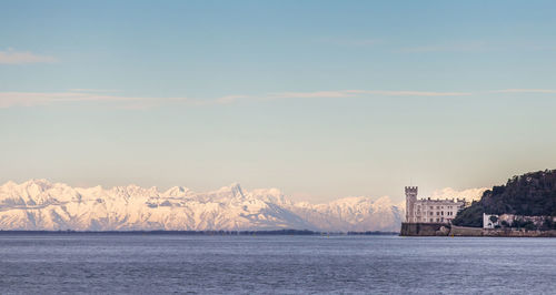 Sea by cityscape against sky