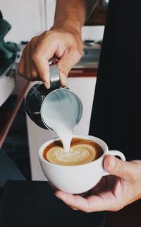 Cropped hand of man pouring coffee in glass