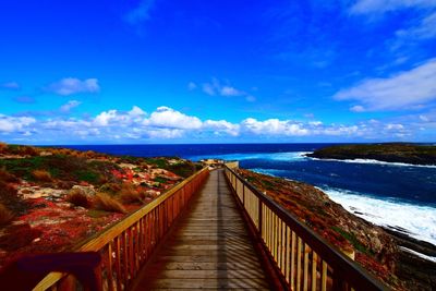 Boardwalk on beach against blue sky