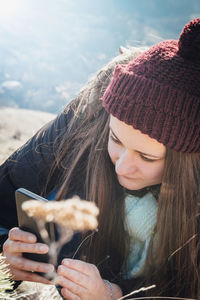 Young woman in warm clothes using mobile phone outdoors