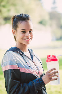 Portrait of smiling young woman holding water bottle