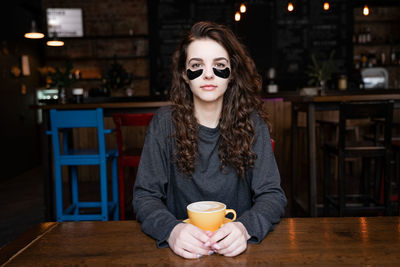 Portrait of young woman drinking coffee at cafe