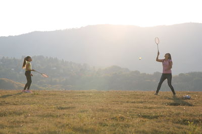 Happy family moments - mother and daughter playing badminton outside