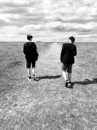 Rear view of friends walking on field