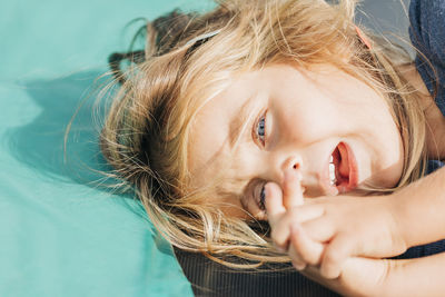Close-up portrait of cute girl with blond hair lying outdoors