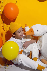 Photo session of a boy in a yellow hat and white t-shirt with a toy bird goose hugging standing 