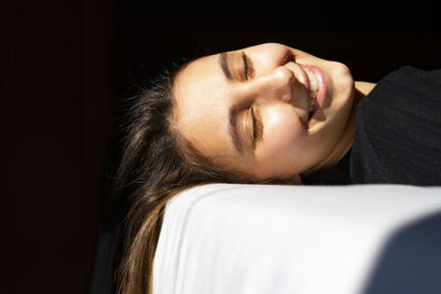 Woman sunbathing on a white bed.