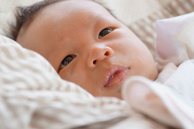 Close-up of baby lying on bed