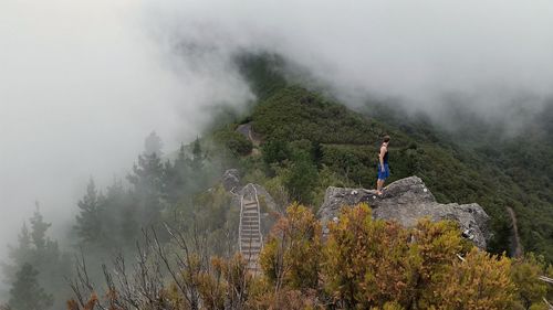 Man standing on mountain in foggy weather