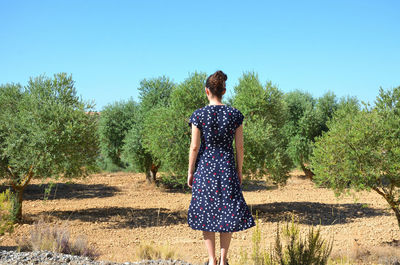 Rear view of woman standing on field against clear sky