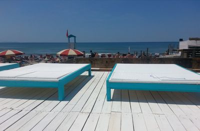 Swimming pool by sea against clear blue sky