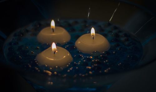 Close-up of lit candles floating in bowl