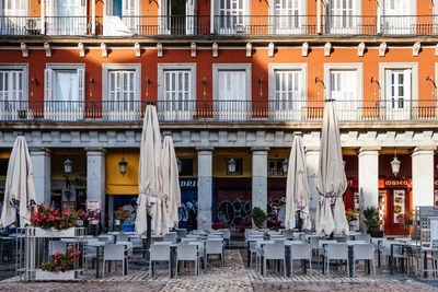 Chairs and tables at sidewalk cafe against buildings in city