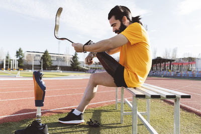 Man adjusting prosthetic leg with screwdriver sitting on bench