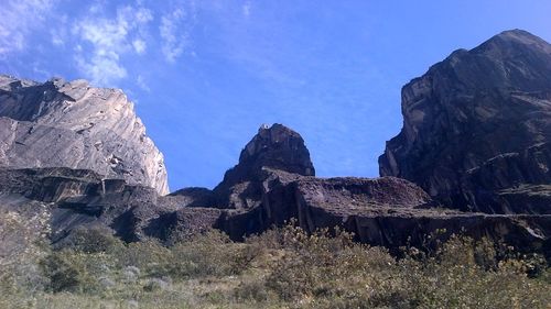 Low angle view of rocky mountain against blue sky