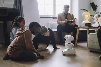 Multiracial students sitting in front of modern robot in innovation lab