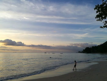 Silhouette man standing on beach against sky during sunset