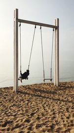 Low angle view of swing at beach against sky