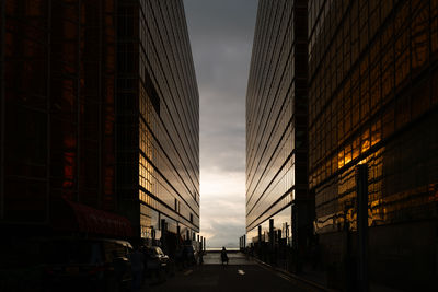 Sillhoette of a woman walking in between two office buildings during the sunset