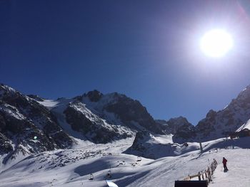 Scenic view of snow covered mountains against sky on sunny day