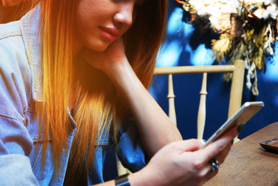 Midsection of woman using mobile phone at table