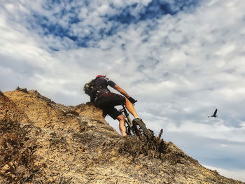 Low angle view of people on rock against sky